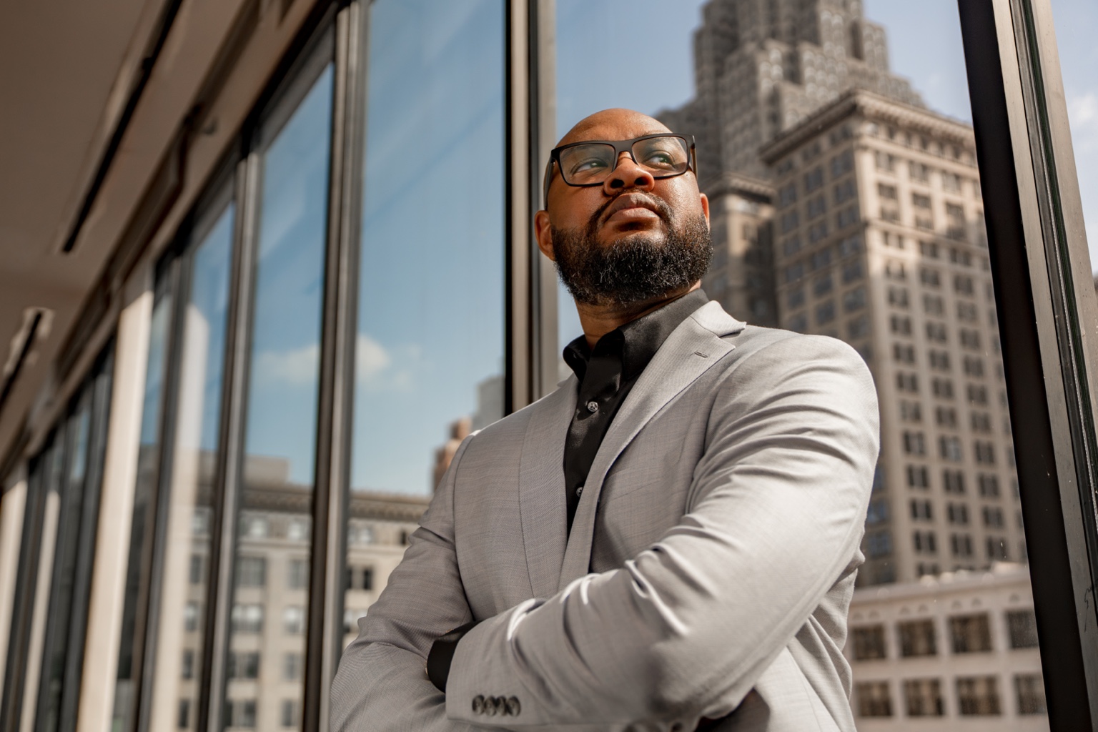 Jerry Johnson beside a window overlooking downtown Detroit